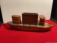 Wooden boat cribbage board with three separate stack pieces assembled on top, showing peg holes for cribbage game on the top surface.