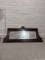 Front view of the antique French mantle style mirror showing carved wooden frame with ornate detailing and rectangular aged mirror glass.