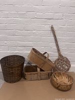 Photo showing all four baskets and the wicker carpet beater against a white brick wall.
