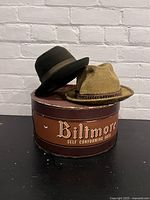 Two vintage Biltmore hats resting on top of an antique round Biltmore hat box with branding.