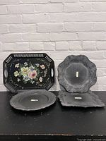 Four serving trays displayed including one floral hand-painted vintage tray and three metal trays with embossed decorative patterns