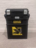 Front view of closed Stanley FatMax toolbox showing black plastic body, silver latches, and yellow logo.