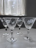 Photo showing several vintage etched cocktail glasses with floral and grapevine patterns on clear glass with long stems.