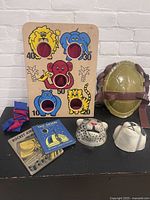 Full lot showing bean bag toss game, Ninja Turtle shell, animal masks, books, and bean bags on a black surface against white brick background.