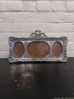 Front view showing the ornate metal frame with bow top and three oval openings.