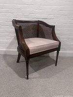 Full view of vintage rattan back armchair showing wooden frame, rattan sides and back, and pink striped upholstered cushion.