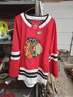 Front view of red Chicago Blackhawks hockey jersey with team logo and stripes.