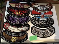 Ten Harley Davidson Owners Group embroidered patches with different years and designs. Some patches have wing, flame, feather, spider web designs embroidered with detailed stitching.