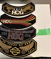 Four curved Harley Owners Group (HOG) embroidered patches displayed on a white surface in good condition with various year and anniversary designs.