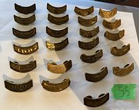 Twenty bronze-colored curved Harley Davidson Owners Group pins dated from 1983 to 2005 displayed on a white background.