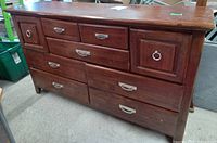 Front view of the old wooden dresser showing seven drawers with metal handles and ring pulls.