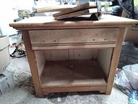 Front view of the old wooden wash stand, showing flat top, open base, and recessed front panel with nail holes.