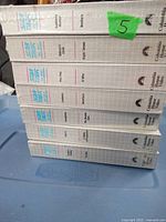 Photo of eight factory sealed Star Trek The Next Generation VHS tapes stacked horizontally showing titles and branding on the spines.