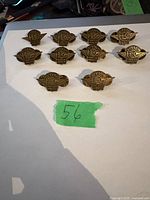 Top view of ten Harley Davidson Ladies of Harley pins arranged on white surface with green sticker numbered 56