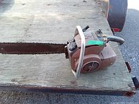 Side view of the vintage Pioneer chainsaw showing the cutting bar, chain, handlebar, and motor housing.