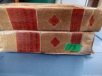 Two volumes of Webster's Universal Dictionary side by side showing worn red and brown spines with text and significant cover wear.