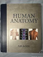 Front cover of the Human Anatomy book showing title, author, and illustrative images of spine and back muscles.