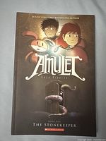 Front cover of Amulet Book One The Stonekeeper showing illustrated characters and title.