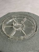 Full top-down view of clear glass 7 compartment divide round relish or appetizer tray on textured gray surface.
