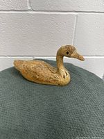 View of the duck figurine from the side showing carved feather details and the shape of the head and beak.