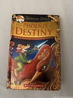 Front cover of the book showing title, author, and illustration of mouse character riding a phoenix.