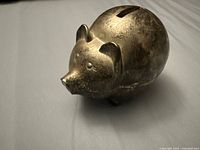 Side/angled view of the silver plated pig-shaped piggy bank showing tarnished condition and details of the pig's face and ears.
