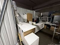 Multiple white desk and console components stacked inside locker