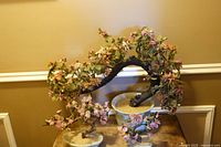 Front view showing large and two smaller glass bonsai trees with pink blossoms and green leaves