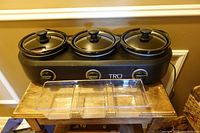 Front view of TRU three-pot slow cooker and acrylic tray