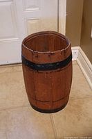 Full view of small wooden barrel showing wood staves, black metal bands and interior