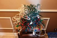 Tangled strands of coloured and clear bulb Christmas lights on small table