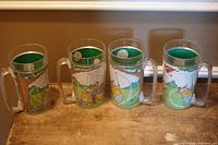 Four clear plastic handled mugs with Winnie the Pooh golf graphics lined on table