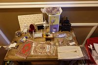 Overview of entire lot on table showing boxed sink, wire furniture, stove, rugs, accessories