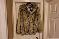 Front view of full faux fur coat on hanger showing overall style and colour
