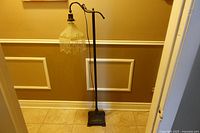 Full view of metal floor lamp with glass shade and bead fringe