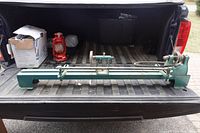 Full view of green bench wood lathe on truck tailgate showing headstock, tailstock, tool rest