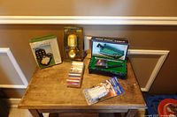 Overall view of tabletop showing all packaged items including mini pool table set, entry alarms, flashlight, boxed accessory case and metallic rolls
