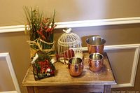 Hammered copper vessels, wire birdcages and faux floral arrangement on wooden table