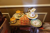 Entire lot on small table showing pitcher, underplate, pizza plates, sunflower cup set, sunflower sugar bowl