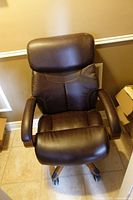 Top view of brown upholstered office chair showing seat, back, armrests, and wheeled base