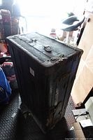 Full view of upright blue wooden trunk with metal hardware showing wear