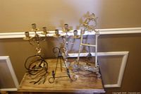 All items on tabletop: two gold-tone candelabra, two easels, one fold-flat holder