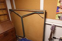 Underside view of folded ping pong table showing metal leg frame and composite wood panel