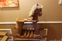 Side view of entire wooden rocking horse on curved rockers showing yarn mane and slatted seat
