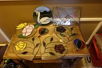Overall view of seven stained glass pieces laid out on table