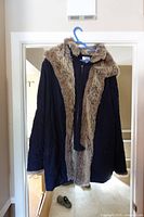 Full view of navy parka hanging, showing tan faux fur lining and hood