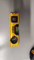 Front view of the 7 inch yellow DEWALT spirit level showing the brand logo and three bubble vials for leveling.