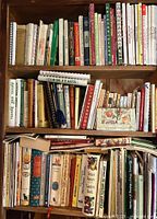 Bookshelf with multiple cookbooks arranged on three shelves