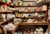Photo of kitchen shelves with various boxed and unpackaged kitchen items including pots, pans, bowls, and small appliances.