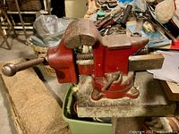 Side view of bright red bench vise mounted on workbench, showing overall condition and dimensions.